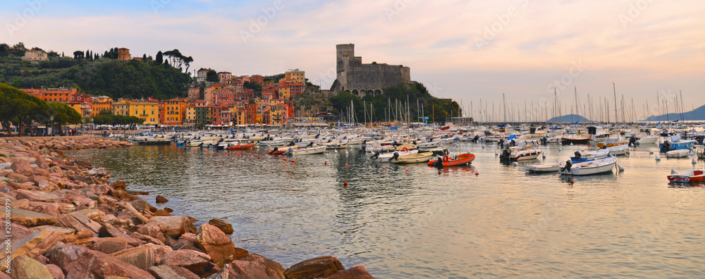 colorful boats and seascape with old castle and blue cloudy sky with sunset  in Lerici in Liguria, Italy