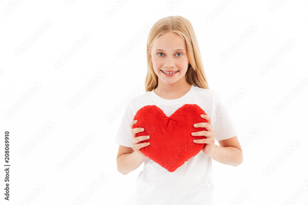 Smiling young blonde girl in casual clothes holding heart toy Smiling young blonde girl in casual clothes holding heart toy