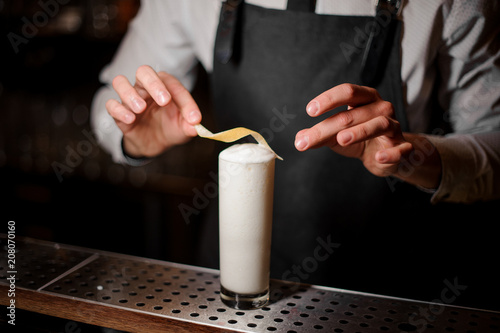 Bartender adding lemon zest to the summer sour white cocktail