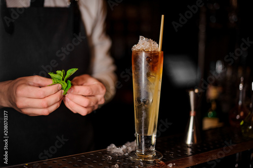 Barman holding a mint leaves near the summer cocktail