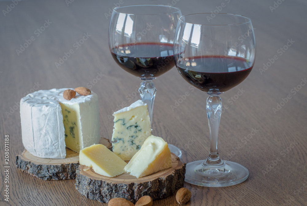 Two glass of red wine with few pieces of cheese at wooden background Two glass of red wine with few pieces of cheese at wooden background