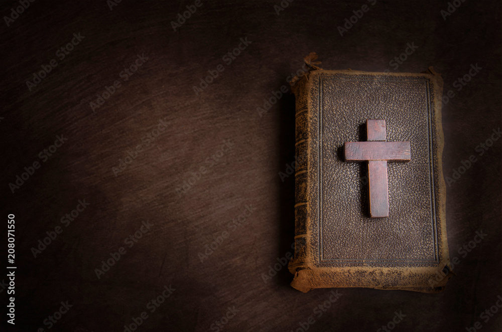 Fototapeta premium Small wooden cross and a bible on a brown table