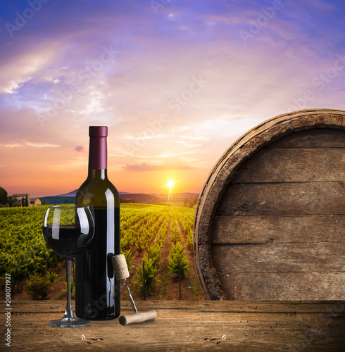 Red wine with barrel on vineyard in green Tuscany, Italy
