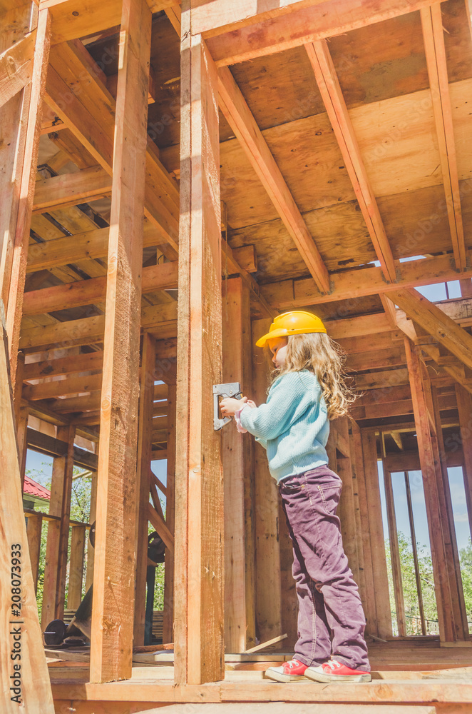 child in a helmet on the construction site of a wooden house child in a helmet on the construction site of a wooden house