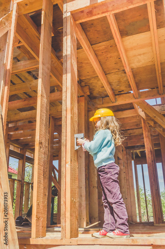 child in a helmet on the construction site of a wooden house
