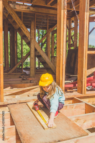 child in a helmet on the construction site of a wooden house