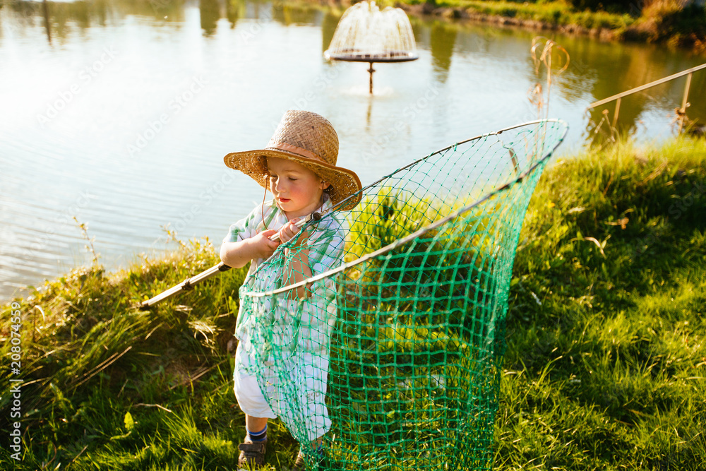 Cute little boy in hat holding big fishing net at the ready. Summer  vacation concept. Stock Photo
