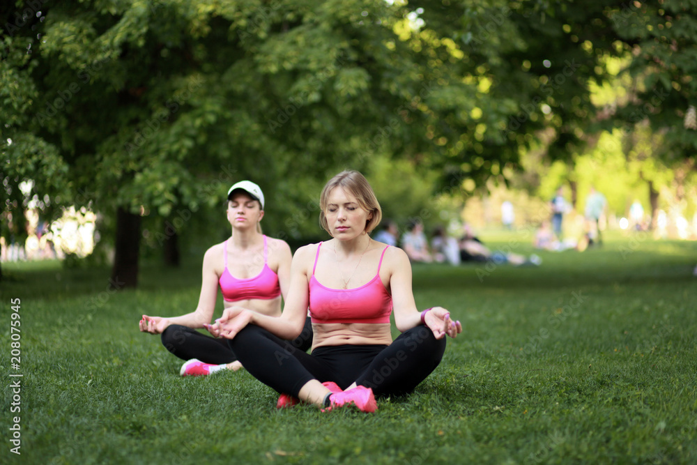 Two young women doing yoga in a park
