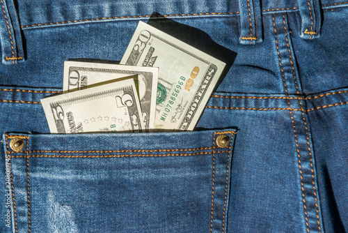 Money in blue jeans pocket- dollar cash concept