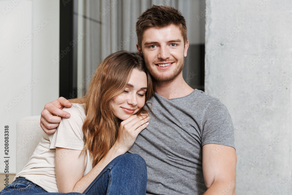 Smiling young couple hugging while sitting together