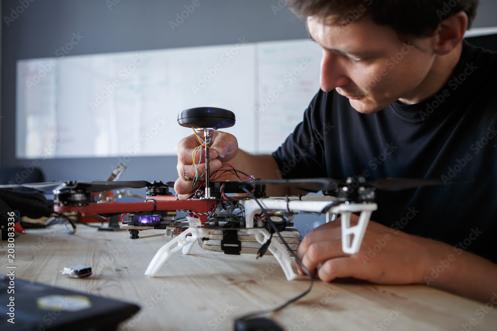 Photo of engineer fixing square copter at table