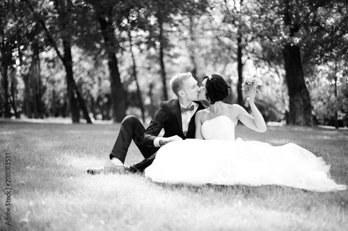 portrait of happy groom and bride sitting in the lawn