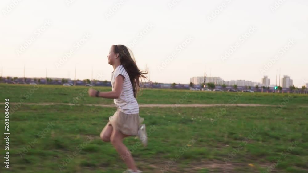 Happy little girl running on grass on city lawn in summer day Happy little girl running on grass on city lawn in summer day