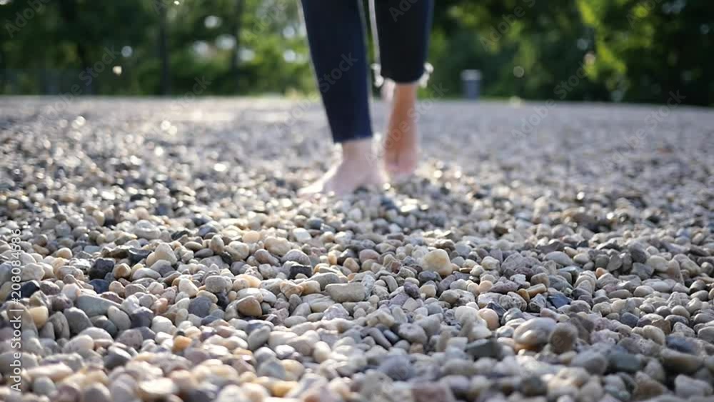 Young woman bare feet walking on pebbles, a useful massage when walking barefooted slow motion
