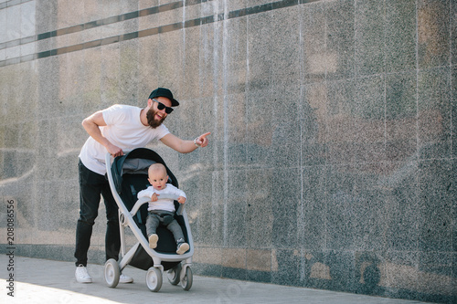 Fotografie Father walking with a stroller and a baby in the city streets