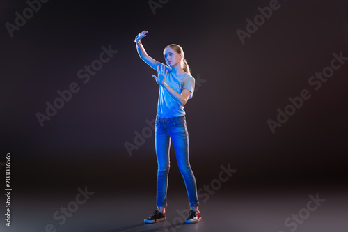 Scientific development. Attractive blonde woman using modern technology while standing against black background