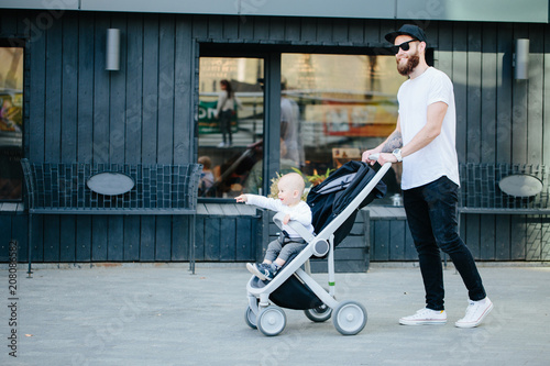 Father walking with a stroller and a baby in the city streets
