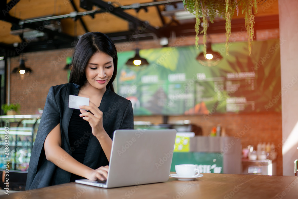 Young woman holding credit card and using laptop computer. Online shopping concept Young woman holding credit card and using laptop computer. Online shopping concept