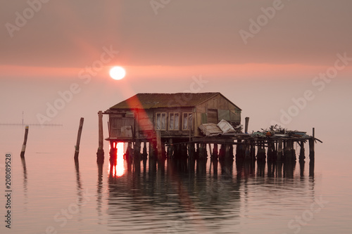 Old fishermen's shack at sunset in Venetian lagoon off the coast of Pellestrina, Venice, Veneto photo