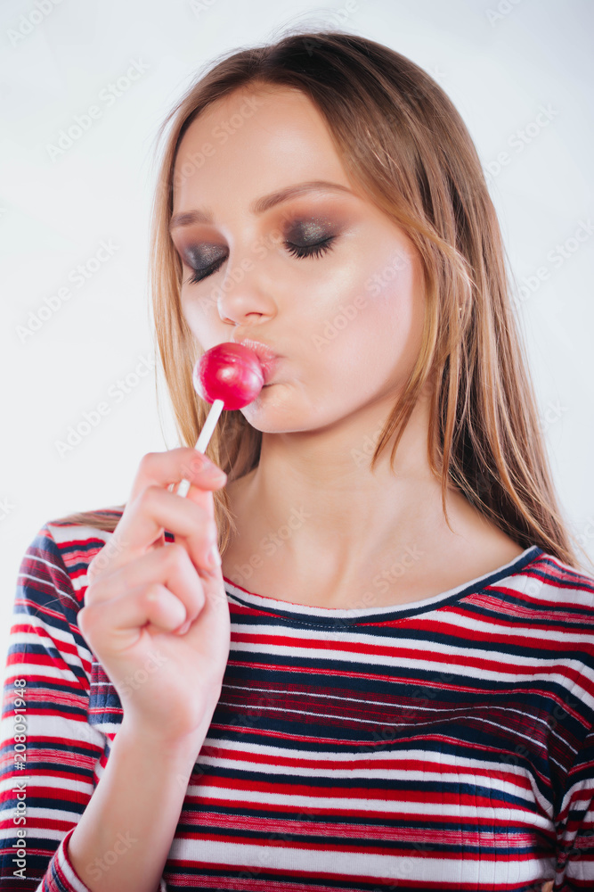 Beautiful girl licking a lollipop.Beautiful woman with creative makeup holding a candy, closeup portrait Beautiful girl licking a lollipop.Beautiful woman with creative makeup holding a candy, closeup portrait