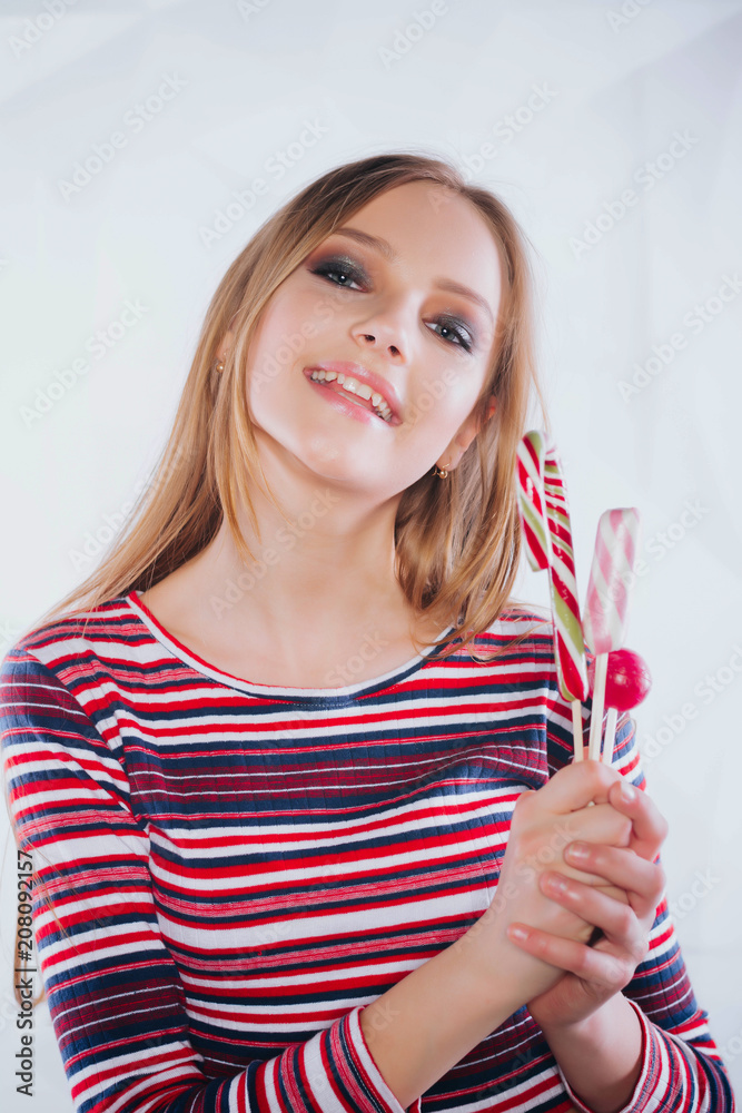 Bright picture of hungry blonde with color lollipop. Beautiful woman with creative makeup holding a candy, closeup portrait Bright picture of hungry blonde with color lollipop. Beautiful woman with creative makeup holding a candy, closeup portrait