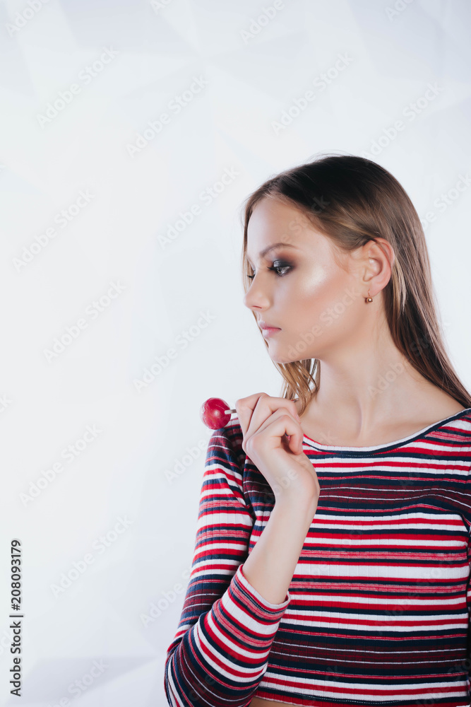 Sexy woman with red lips holding lollipop, beauty closeup. Beautiful woman with creative makeup holding a candy, closeup portrait Sexy woman with red lips holding lollipop, beauty closeup. Beautiful woman with creative makeup holding a candy, closeup portrait