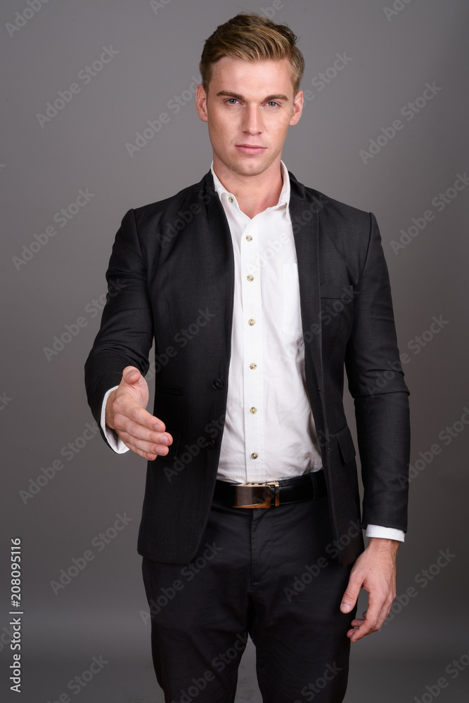 Fototapeta premium Young handsome businessman with blond hair wearing suit against 