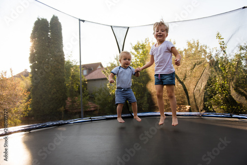 Siblings jumping together on trampoline