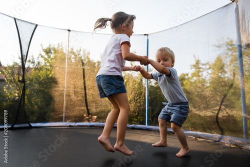 Adorable siblings bouncing together on trampoline