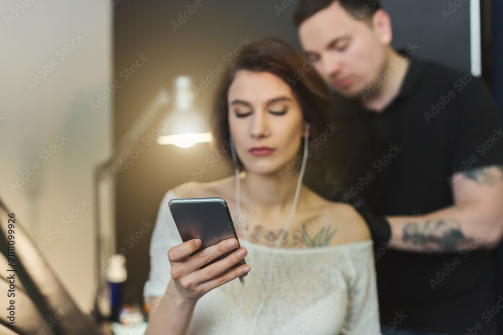 Woman listening to music while doing tattoo