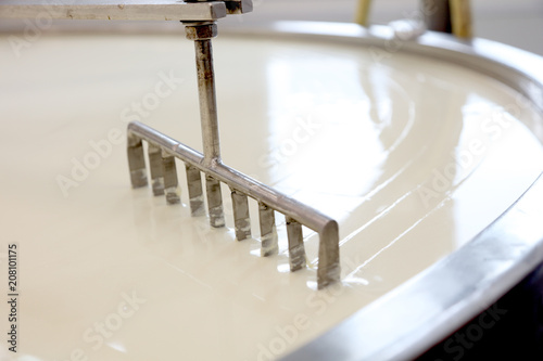 Machine slicing through curdled cheese curds in vat photo