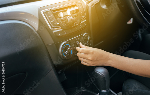 Hand of woman turning on car air conditioning system,Button on dashboard in car panel