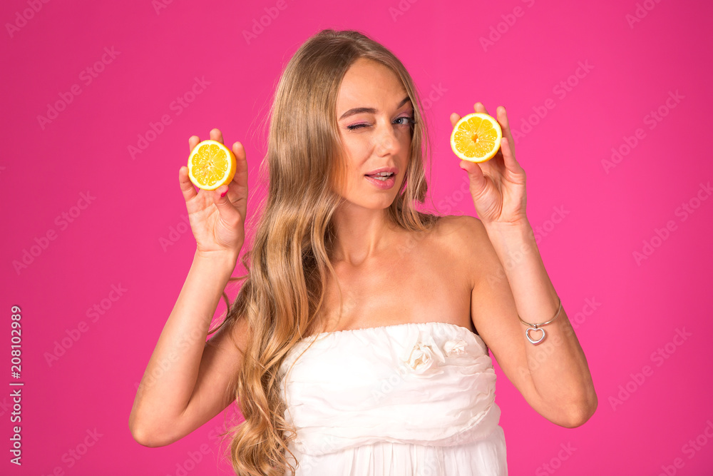 Beautiful blonde woman with lemons in hands on a pink background. Beautiful blonde woman with lemons in hands on a pink background.