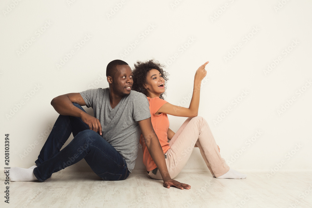 Black couple looking up sitting on floor Black couple looking up sitting on floor