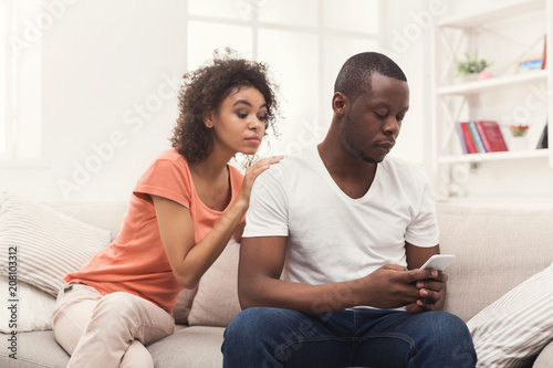 African-american couple at home, man texting