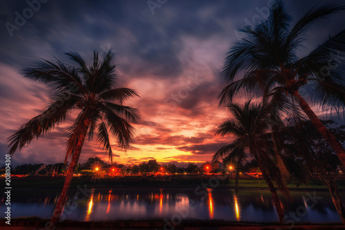 Silhouette coconut palm trees near the river at sunset. Vintage tone. © nuttawutnuy
