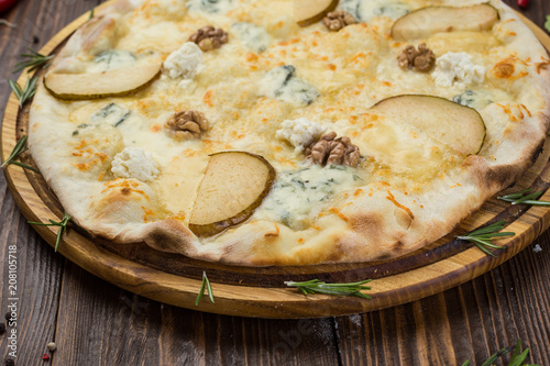 Italian pizza four cheese quattro fromaggi with pear and walnut on a rustic wooden board background photo