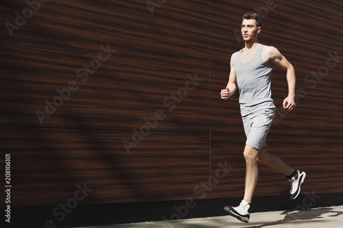 Young man running in city copy space