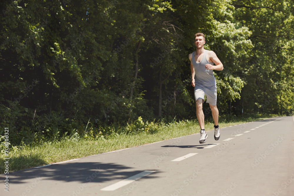 Young man jogging on treadmill in park, copy space Young man jogging on treadmill in park, copy space