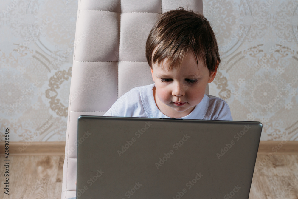 the boy is sitting on a chair and is holding a laptop the boy is sitting on a chair and is holding a laptop