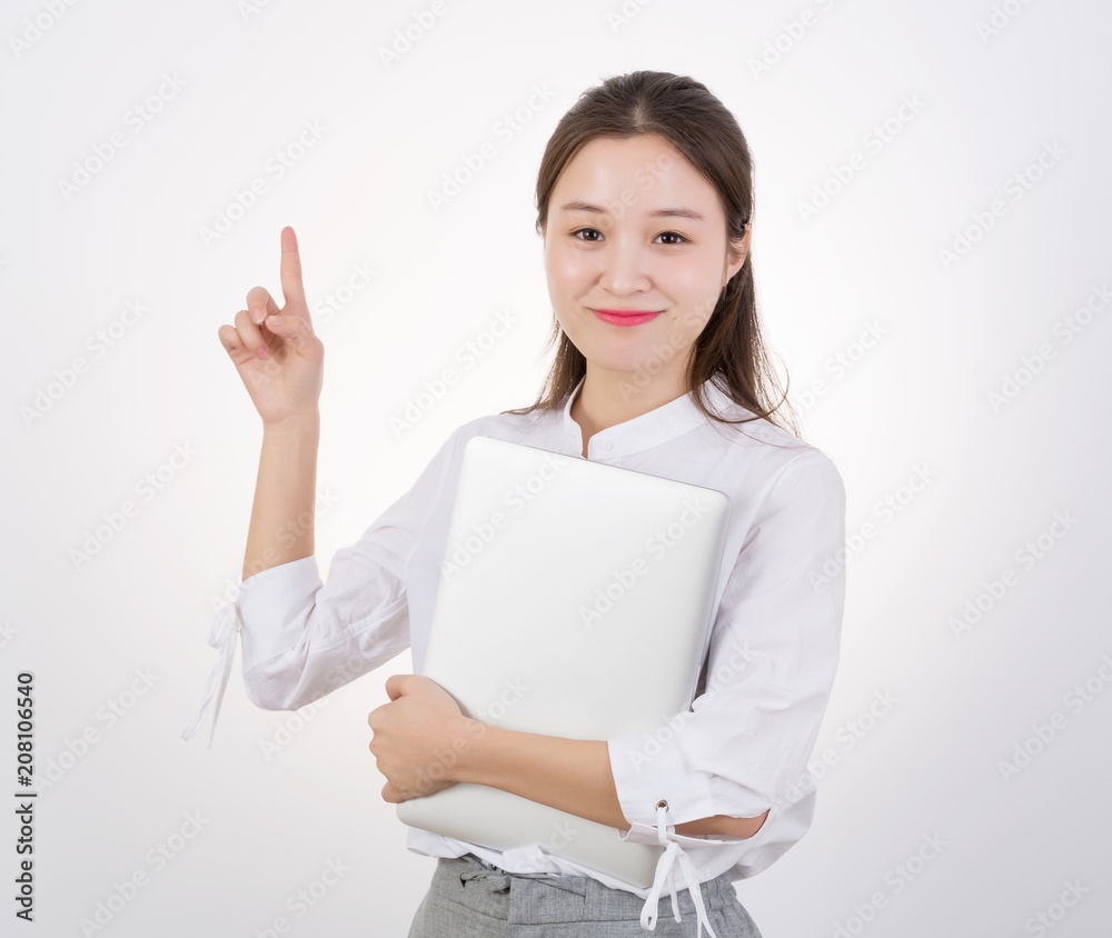 Smiling beautiful young woman holding laptop and pointing away Smiling beautiful young woman holding laptop and pointing away
