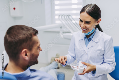Doctor showing patient how to brush teeth on jaws model