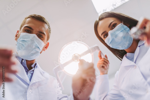 dentist and assistant holding dental tools