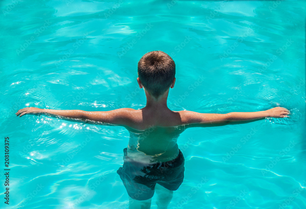 Boy exercising in outdoor swimming pool, learning to swim