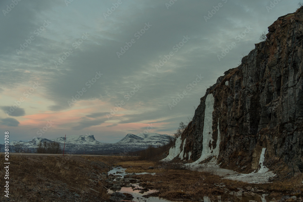 Frozen waterfall in Abisko National Park at Torneträsk Lake at sunset / Lapland, Sweden