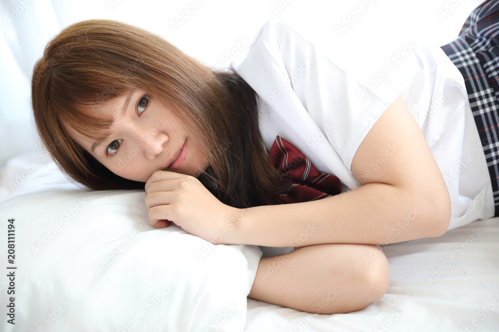 Portrait japanese school girl costume sleeping and smile in white tone bed room Portrait japanese school girl costume sleeping and smile in white tone bed room