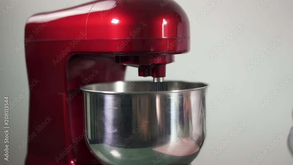 Whipping of cream in metal bowl with electric mixer machine. Mixing white cream with red stand mixer Whipping of cream in metal bowl with electric mixer machine. Mixing white cream with red stand mixer