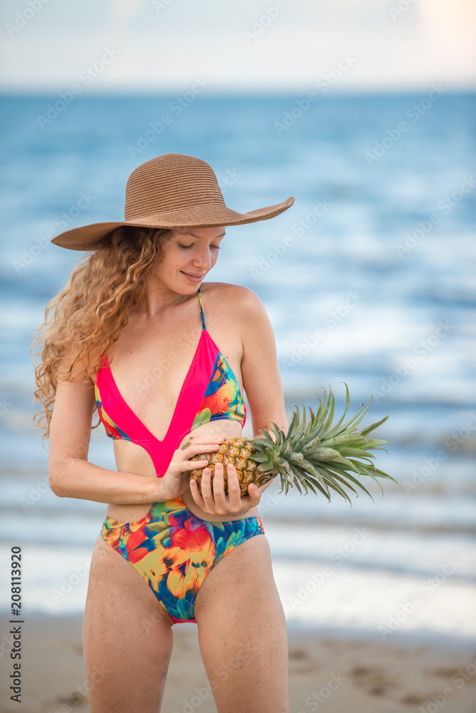 Portrait happy woman with long blonde curly hair holding pineapple on the beach with enjoying and refreshing, summer beach relaxing time concept.