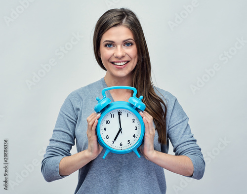 Young woman holding big blue alarm clock.