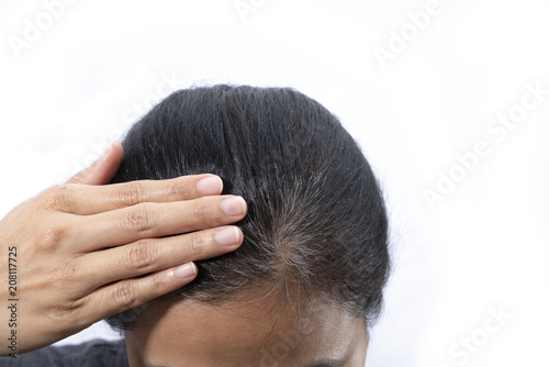 Young woman shows her gray hair roots isolated on white background